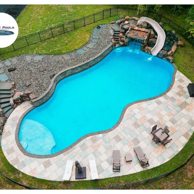 In-ground pool with a stone waterfall and slide feature built by Patriot Pools in a wooded backyard near Centreville, MD