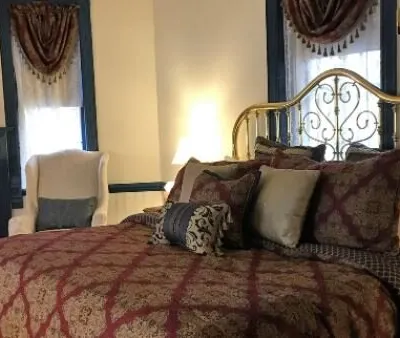 Guest bedroom with a brass bed and burgundy patterned bedspread at The Parsonage Inn in St. Michaels, MD
