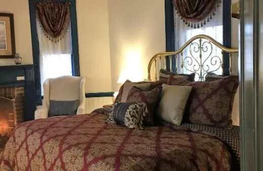 Guest bedroom with a brass bed and burgundy patterned bedspread at The Parsonage Inn in St. Michaels, MD