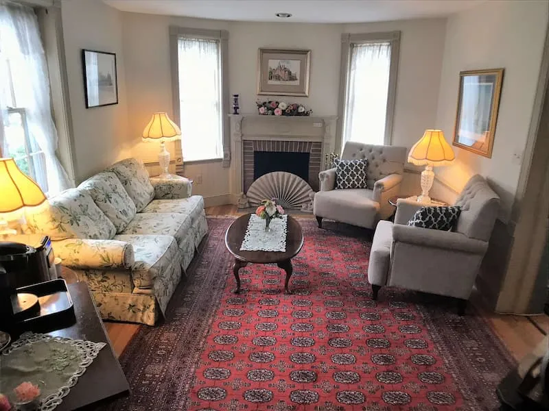 Historic Victorian parlor with a floral sofa and fireplace at The Parsonage Inn in St. Michaels, MD